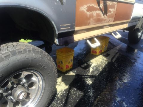1985 Ford F-350 - Truck side and wheel with yellow buckets supporting the frame.