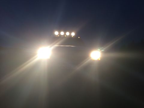 1993 Ford Bronco - Truck with headlights and auxiliary lights on at night.