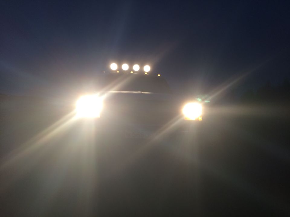 Front view of a truck at night with headlights and roof-mounted off-road lights illuminated