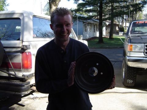 1988 Ford Bronco - Man holds a brake drum in front of a 1988 Ford Bronco and a pickup truck.