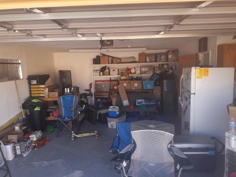 1957 Poison Spyder ZL 71 - A cluttered garage scene contains storage shelves, a refrigerator, a tool chest, and various items on the floor.