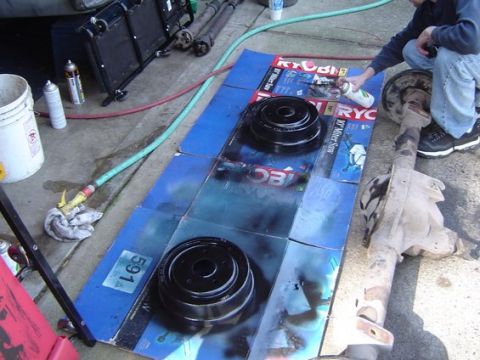 1988 Ford Bronco - Spray painting brake drums and a differential outdoors on cardboard.