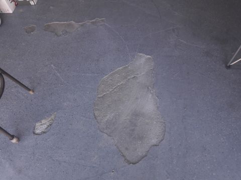 1957 Poison Spyder ZL 71 - The concrete floor shows several water stains and a portion of a chair leg is visible.