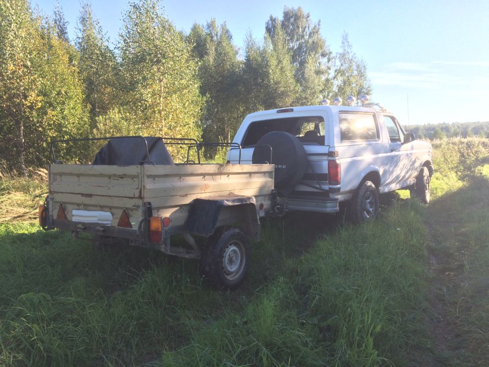 White 1993 Ford Bronco with spare tire on rear, towing a trailer