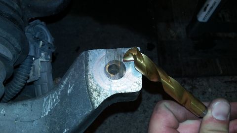 2000 Pontiac Grand Prix - A drill bit is positioned to enter a threaded hole on a metal component, likely for automotive repair.