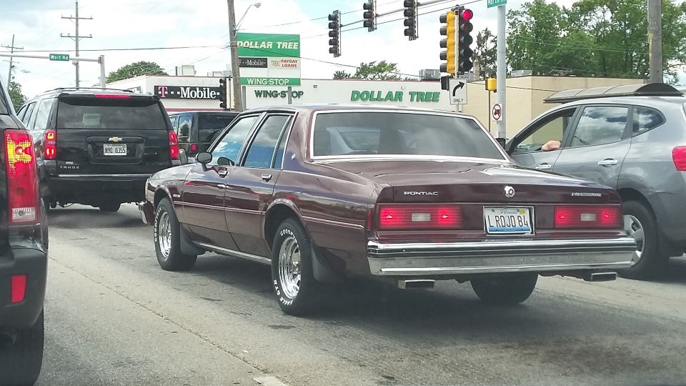 Maroon Pontiac Parisienne sedan with chrome trim and a license plate reading 'L ROJO 84'