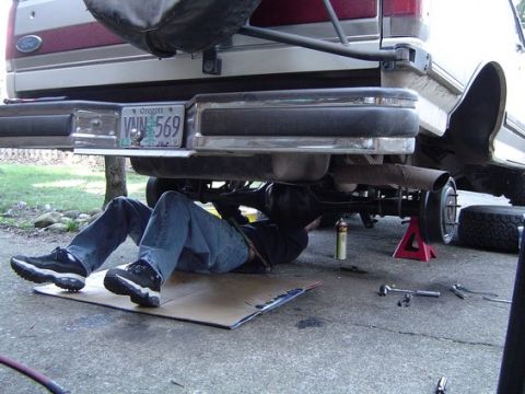 1988 Ford Bronco - A person works on the rear axle of a 1988 Ford Bronco, which is supported by jack stands.