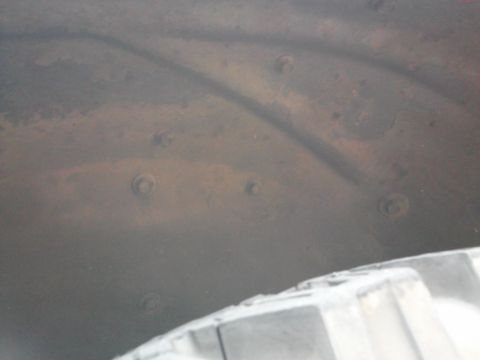 1998 Chevrolet C/K Pickup - The interior of a wheel well shows some rust and bolts, with a portion of the tire visible.