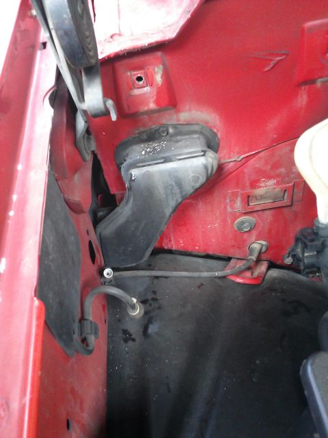 1998 Chevrolet C/K Pickup - Close-up view of engine bay components, including black ducting and hoses, on a red vehicle.