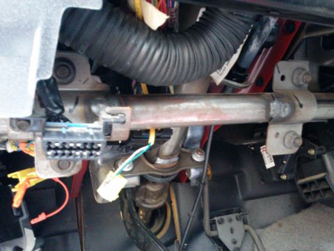1998 Chevrolet C/K Pickup - The photo shows the complex wiring and steering column components located beneath the dashboard of a vehicle.
