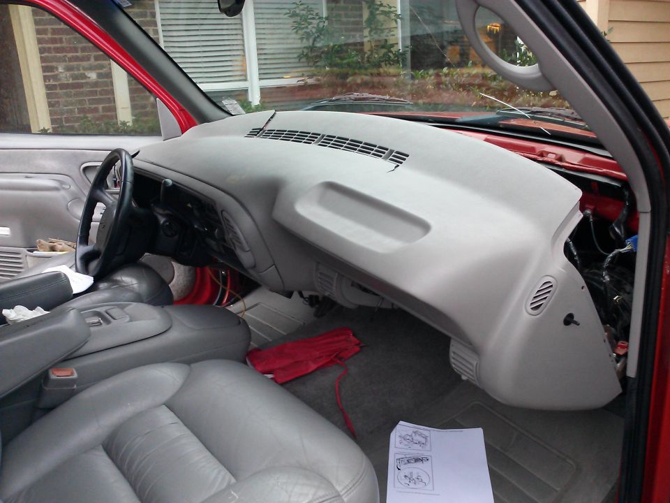 Red truck interior with gray dashboard removed, showing exposed wiring and gray leather seats