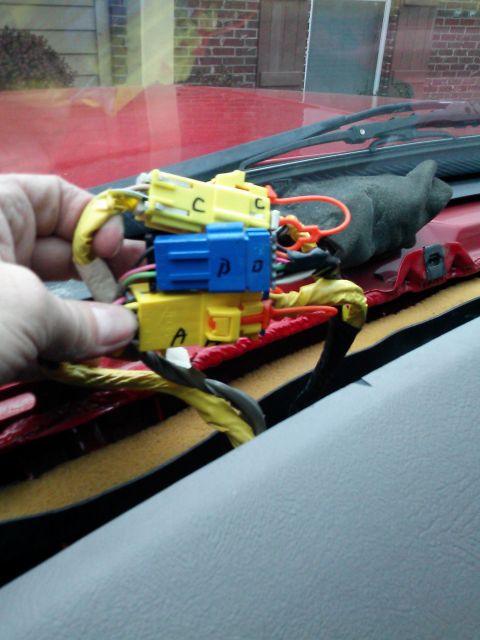 1998 Chevrolet C/K Pickup - A hand holds electrical connectors, likely for a dashboard repair, against a red interior.