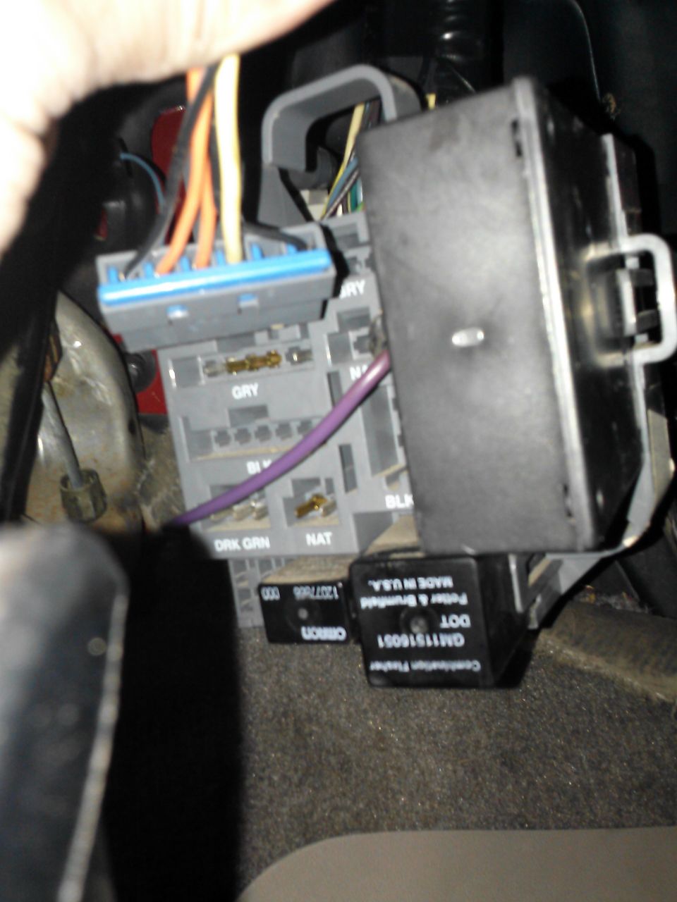 Close-up of vehicle interior wiring harness and fuse box with visible labels like GRY, NAT, and BLK