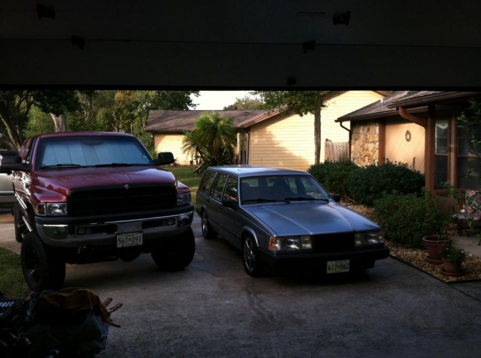 Red Dodge Ram pickup truck and silver Volvo station wagon in a driveway.