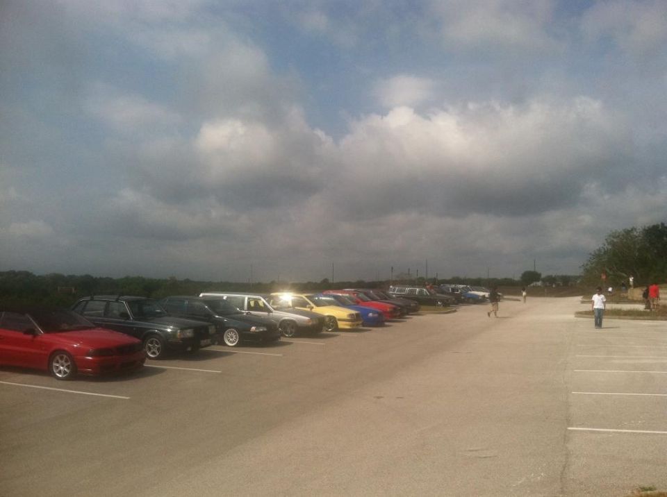 Line of parked cars including a red convertible and several sedans and wagons.