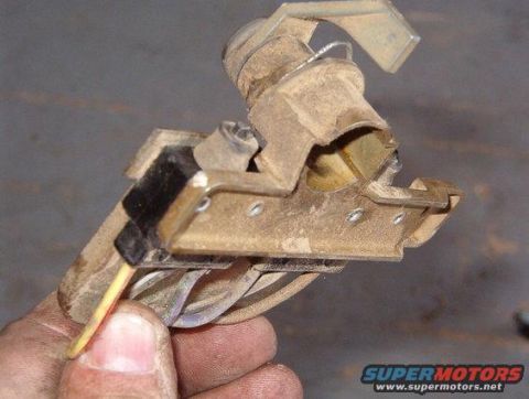 1994 Ford Bronco - Photograph of a tailgate lock and switch component held in hand, not a technical document.