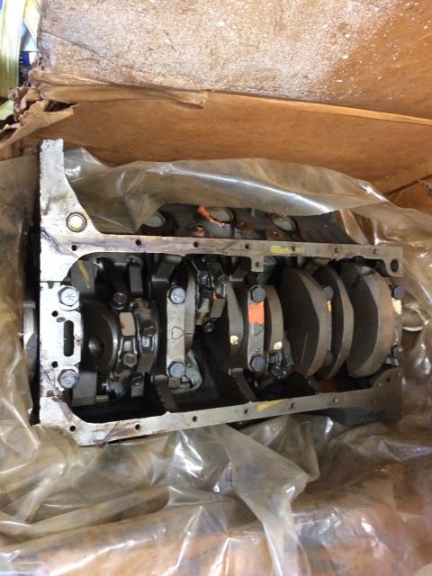 1973 Ford F-100 - A disassembled V8 engine block with crankshaft and connecting rods is shown, partially covered by plastic sheeting and cardboard.