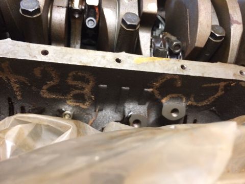 1973 Ford F-100 - A close-up view of the engine block with numbers "28" chalked onto the side. The crankshaft and connecting rods are visible above the block.