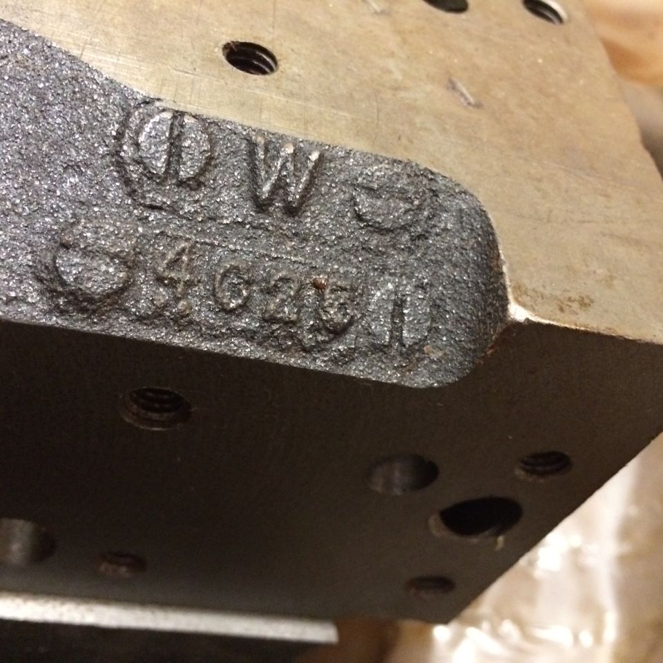 Cast-in text DW 3462511 on a dark metal part.