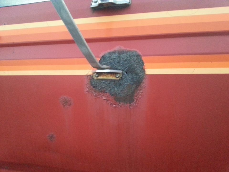 Sanded rust spot on a red truck door with grinder