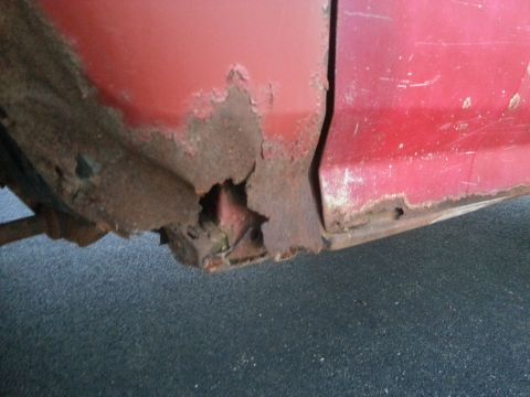 1984 Ford Bronco - Photo of corrosion and rust-through at the lower fender of a red truck.
