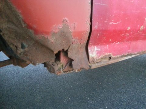 1984 Ford Bronco - Photo of corrosion and rust-through at the lower fender of a red truck.