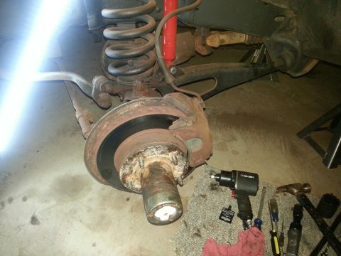 1984 Ford Bronco - Photo of a front brake rotor and hub with coil spring and tools laid out beside it.