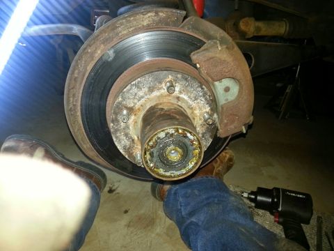 1984 Ford Bronco - Photo of a rusty front brake rotor and wheel hub viewed from below during service.