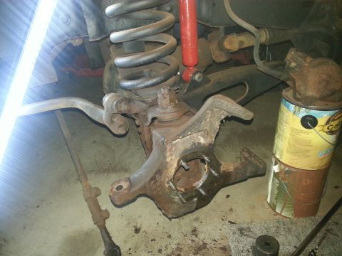 1984 Ford Bronco - Photo of a rusty steering knuckle, coil spring and red shock with a parts can nearby.