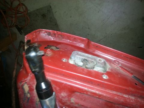 1984 Ford Bronco - Photo of a pneumatic ratchet working on a latch striker mounted to a red tailgate panel.