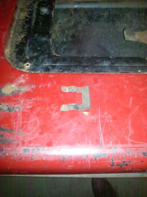 1984 Ford Bronco - Photo of a C-shaped sheet-metal patch welded onto a scratched and weathered red panel.