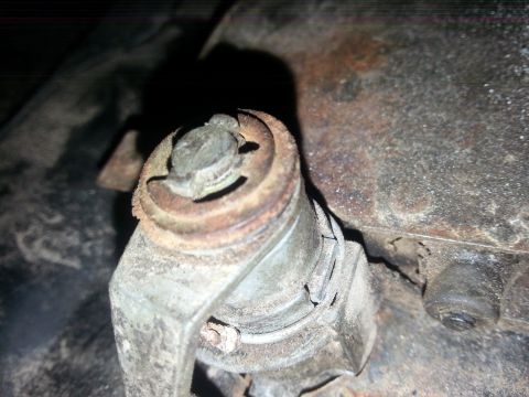 1984 Ford Bronco - Photo of a corroded suspension joint with a castellated nut on the underside of a vehicle.
