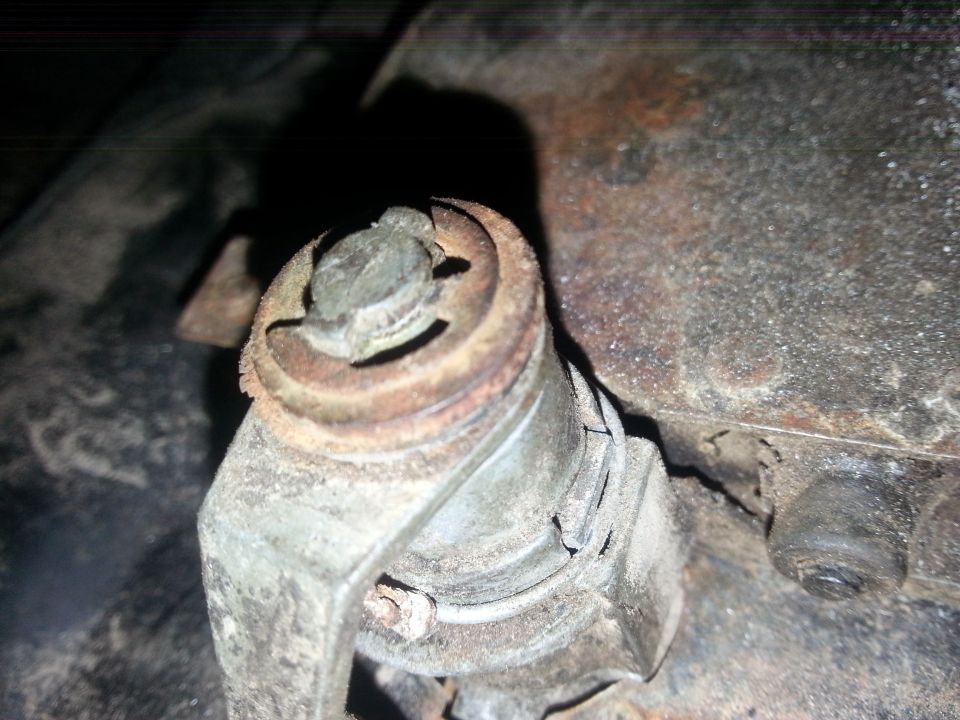 Corroded suspension joint with a castellated nut underneath a vehicle