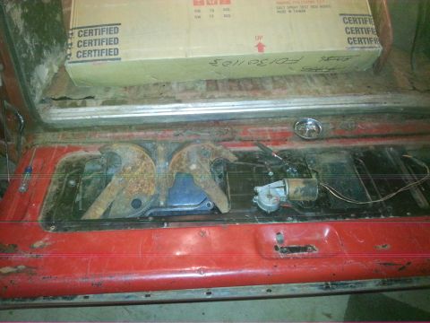 1984 Ford Bronco - Photo of an open red tailgate showing internal latch hardware and a labeled cardboard box behind.