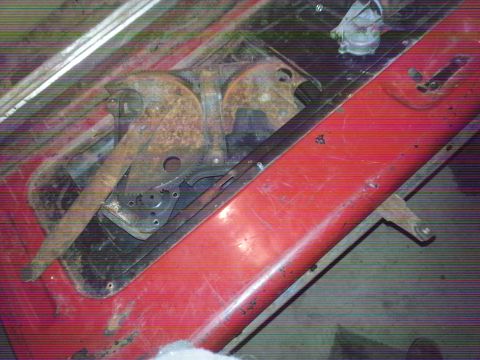 1984 Ford Bronco - Photo of a red tailgate interior with latch and linkage hardware seen through a glass window.
