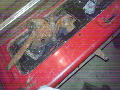1984 Ford Bronco - Photograph of a red vehicle body panel and rusty bracket pieces during a restoration, not a technical document.