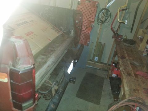 1984 Ford Bronco - Photograph of a truck bed and frame supported in a garage during restoration, not a technical document.