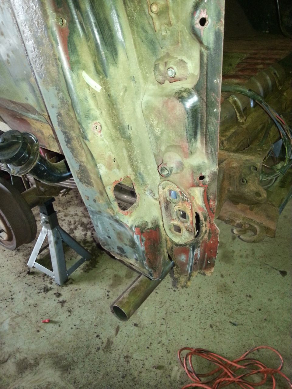 Photo of a sanded green-primer truck body panel on jack stands