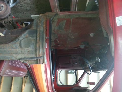 1984 Ford Bronco - Photograph of a red pickup interior with the door open during restoration, not a technical document.