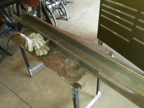 1984 Ford Bronco - Photograph of a fabricated steel body section on a bench with gloves, not a technical document.