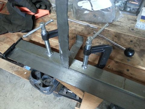 1984 Ford Bronco - Photograph of welded steel pieces clamped on a bench during fabrication, not a technical document.