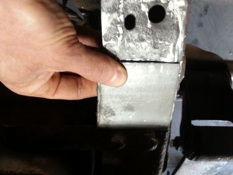 1984 Ford Bronco - Photo of a hand holding a freshly welded sheet-metal bracket with drilled holes.