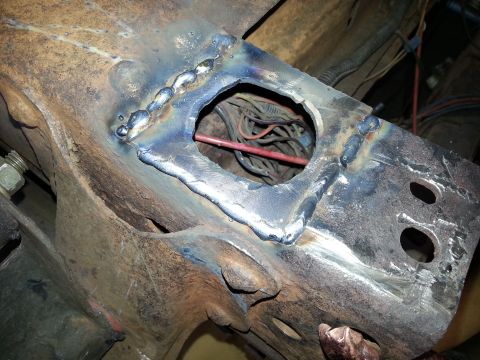 1984 Ford Bronco - Photo of a welded reinforcement plate on a vehicle frame with wiring routed through a hole.