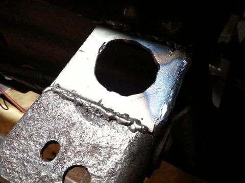 1984 Ford Bronco - Photo close-up of a welded metal bracket with a large bored hole and weld beads.