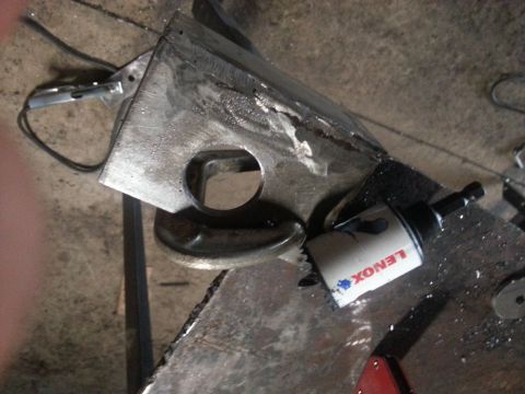 1984 Ford Bronco - Photo of a welded metal bracket and a Lenox hole saw on a workbench, not a document.