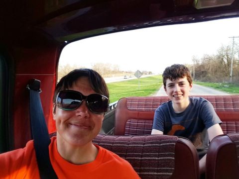 1984 Ford Bronco - Photo of two people riding inside a vehicle with a red plaid bench seat, not a document.