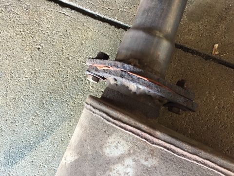 1984 Ford Bronco - Photo of a bolted exhaust flange and muffler under a vehicle, not a document.