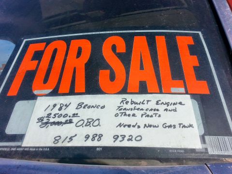 1984 Ford Bronco - Photo of a handwritten For Sale window sign listing a 1984 Bronco with rebuilt engine and phone number, not a technical document.