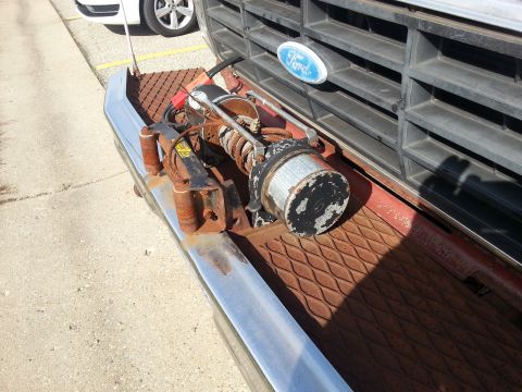 1984 Ford Bronco - Photo of a worn winch mounted on the front bumper of a Ford truck, not a document.