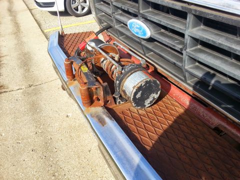 1984 Ford Bronco - Photo of a worn winch mounted on the front bumper of a Ford truck, not a document.